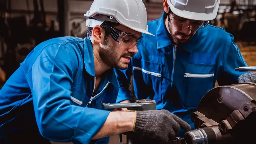 Dois técnicos de capacete conferindo informações em tablet na fábrica
