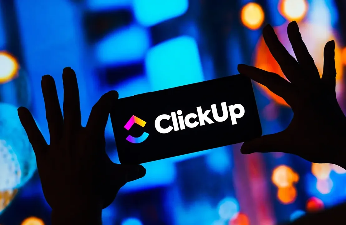 Silhuetas de mãos diante de um letreiro luminoso com a marca ClickUp